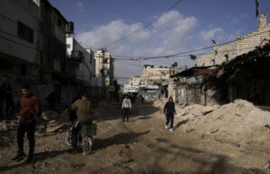 Палестинци се разхождат по повреден път в бежанския лагер 
