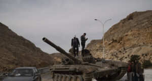 Сирийци стоят върху изоставен танк на силите на Дамаск