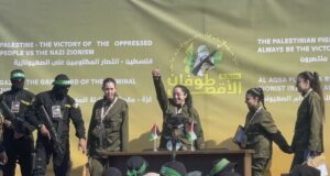 Четирите израелски заложнички на подиума на площад "Палестина" в град Газа, заобиколени от въоръжени бойци на палестинската групировка "Хамас", малко преди да бъдат предадени на Международния комитет на Червения кръст.