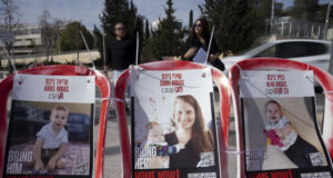 Плакати със снимките на убитите Ариел и Кфир Бибас и тяхната майка, 19 февруари 2025 г.