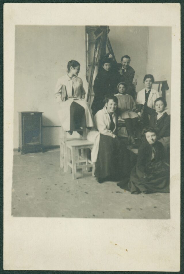 Бистра Винарова (крайната долу вдясно), нейни състудентки (Зошка, полякиня, горе вляво и Хилда Дьорнер, най-долу), проф. Хофман и момиче модел (в средата) в ателието на Ханс Хофман. Мюнхен. 1916 – 1917 г.ЦДА, ф. 77К, оп. 5, а.е. 207, л. 22